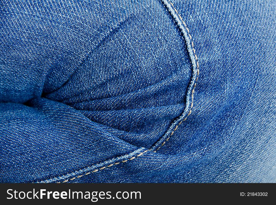 Women's knee in jeans with folds closeup. Women's knee in jeans with folds closeup