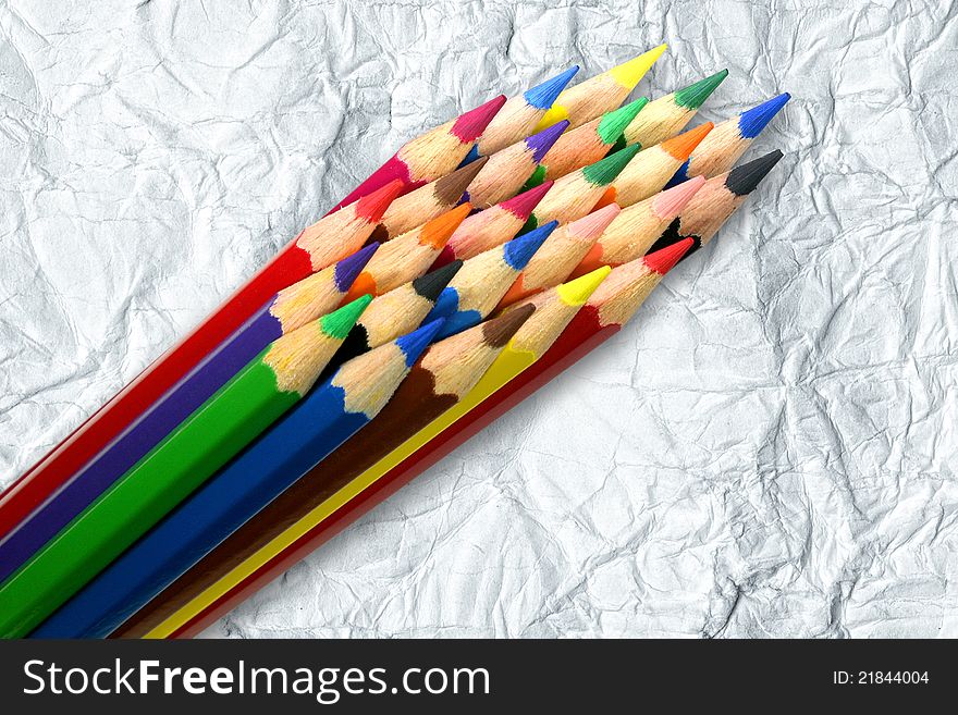 A stack of colored pencils on crumpled paper background