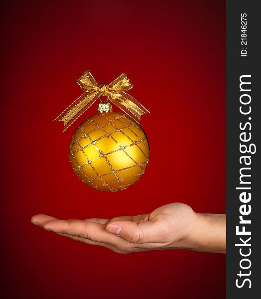 A beautiful Christmas ball decorated with a golden ribbon above someone's hand. Celebrating Christmas. Caring at Christmas. A beautiful Christmas ball decorated with a golden ribbon above someone's hand. Celebrating Christmas. Caring at Christmas.