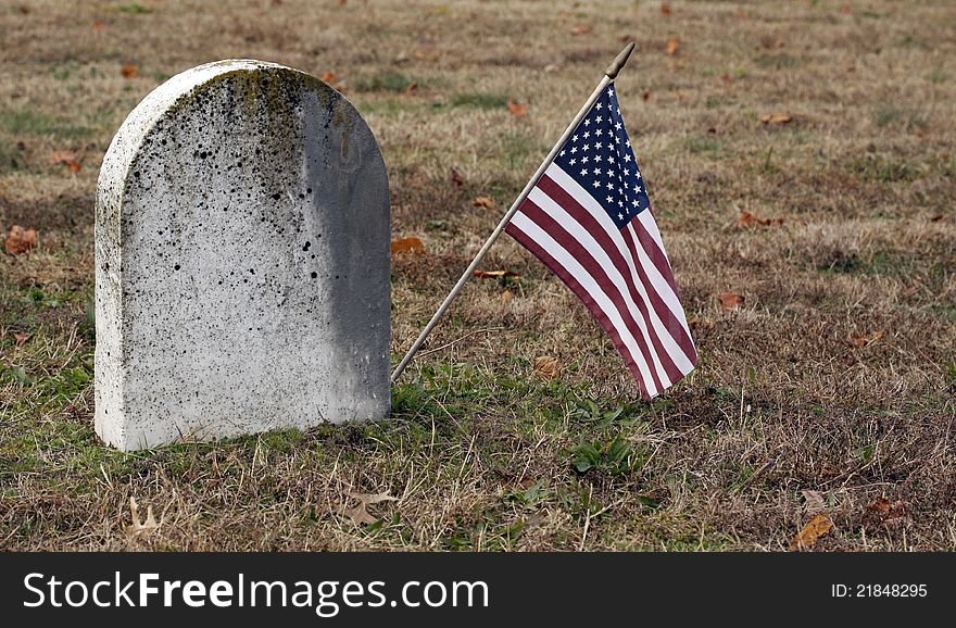 American flag next to old tombstone. American flag next to old tombstone.