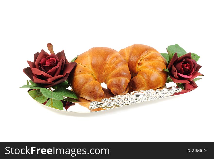 Fresh croissants and red roses on a white background. Fresh croissants and red roses on a white background