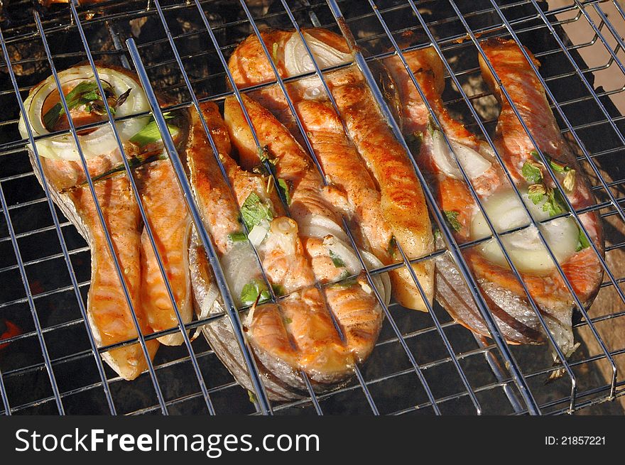 Tasty pieces of salmon cooking on a grill