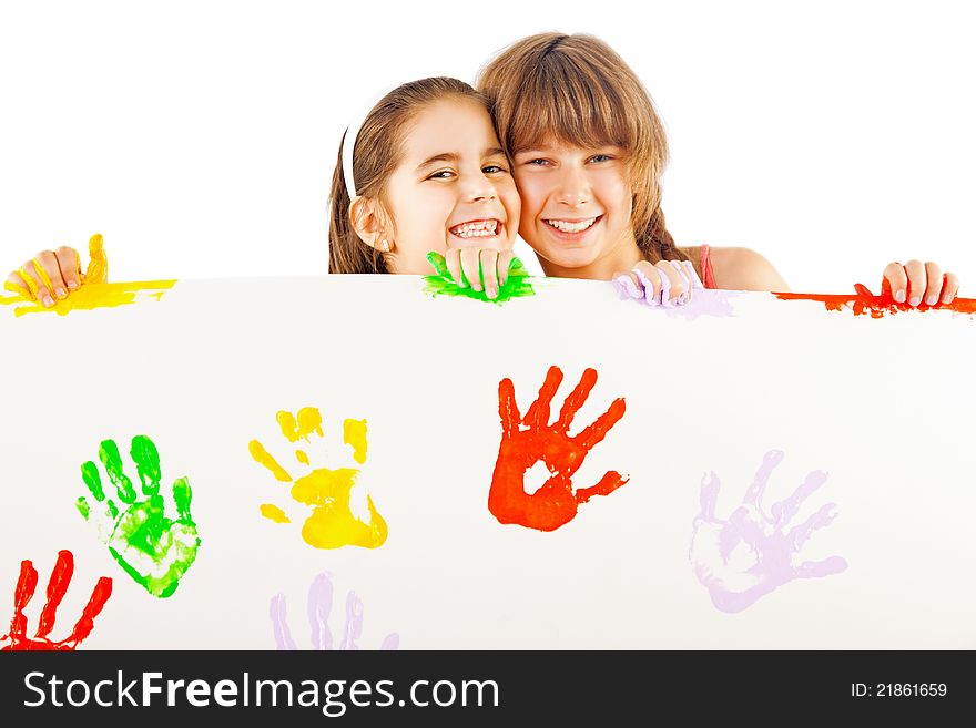 Two smiling little girls holding white sheet with colourful hand prints. Two smiling little girls holding white sheet with colourful hand prints