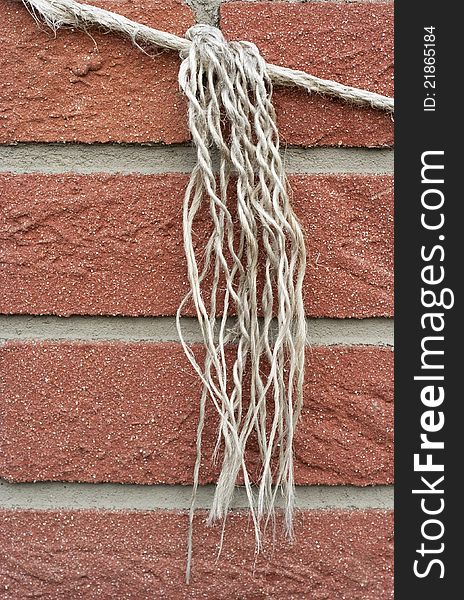 Knotted rope on a brick wall, raw . Knotted rope on a brick wall, raw
