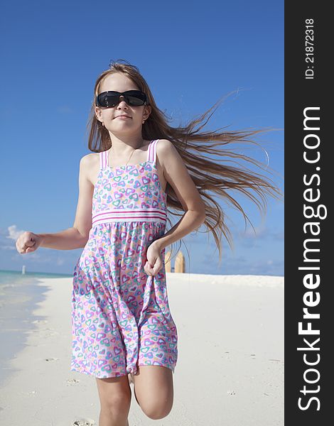 A beautiful Caucasian happy girl child running and playing on the beach enjoying the summer. A beautiful Caucasian happy girl child running and playing on the beach enjoying the summer