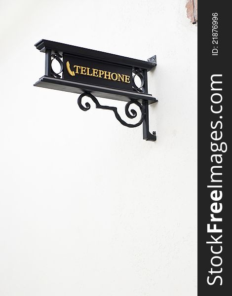 Wrought-iron telephone sign on white wall