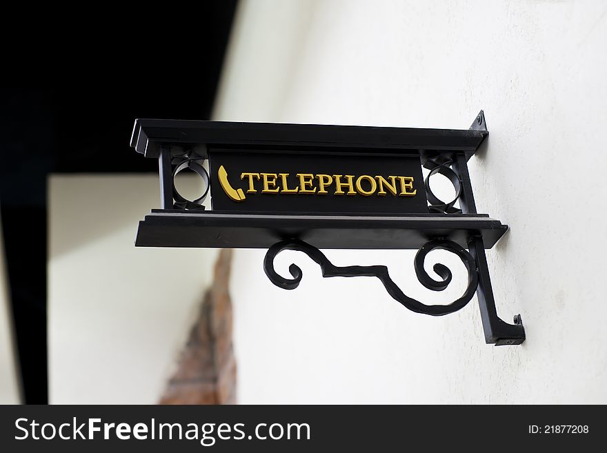 Wrought-iron telephone sign on white wall