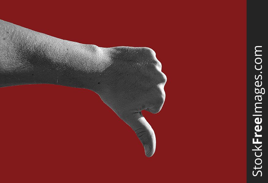 Black and white photography of male hand showing thumb down gesture isolated on dark red  background