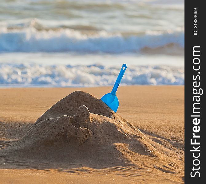 Blue shovel in the yellow sand near sea