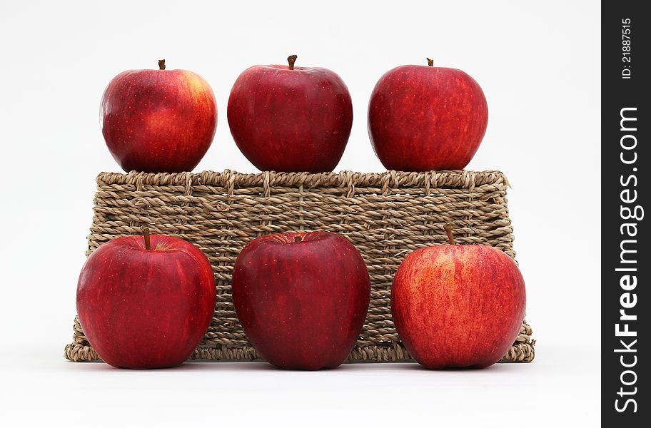Six Gala apples with an upturned woven seagrass basket. Isolated on a white background. Six Gala apples with an upturned woven seagrass basket. Isolated on a white background.