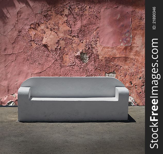 White marble stone sofa on cracked plaster wall background. White marble stone sofa on cracked plaster wall background