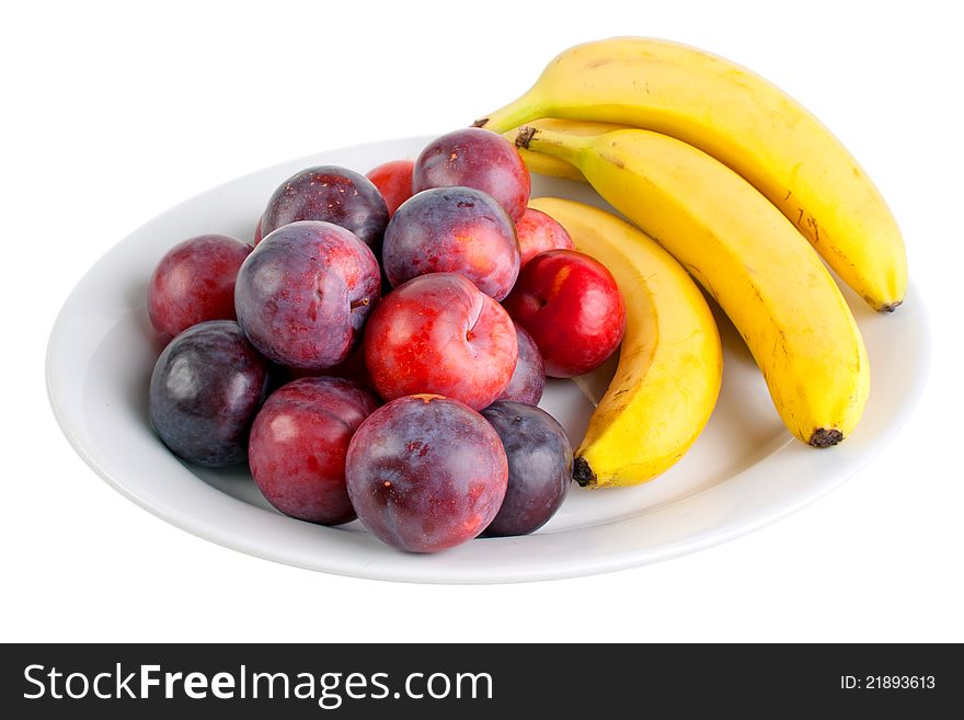 Plums and bananas on the plate, isolated on white