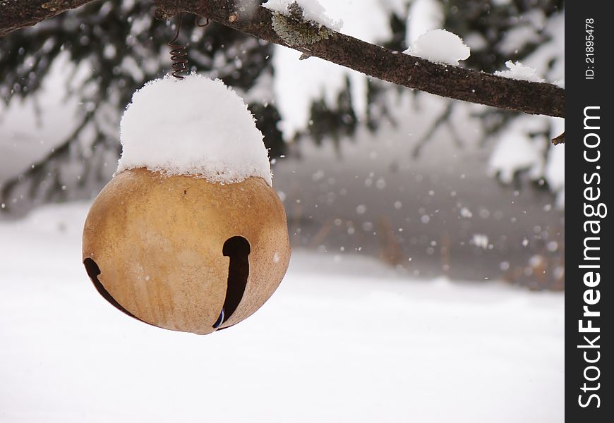 Snow flakes softly falling on a large bell hanging in a tree. Snow flakes softly falling on a large bell hanging in a tree.