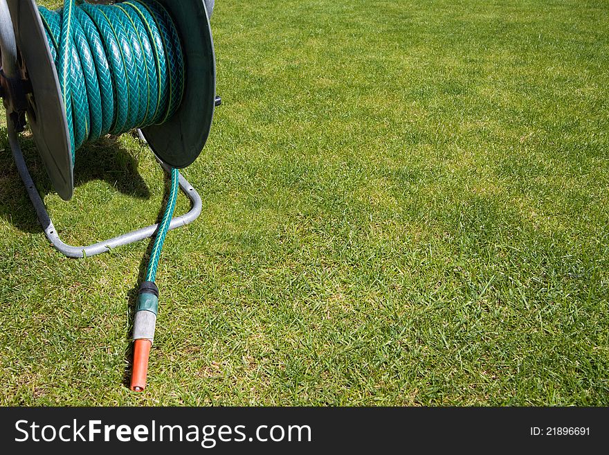 Garden equipment - coiled hose pipe on the green grass background with copy space. Garden equipment - coiled hose pipe on the green grass background with copy space.