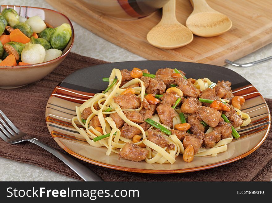 Dinner plate with chicken cashew over noodles with bowl of vegetables. Dinner plate with chicken cashew over noodles with bowl of vegetables