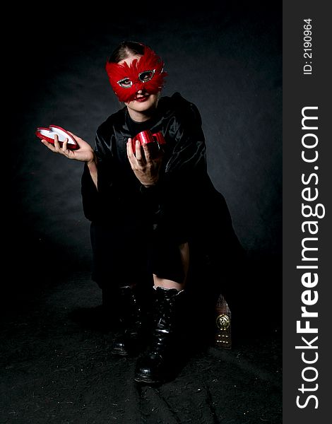 Women in red mask with open box in hands. Make-up black background. Women in red mask with open box in hands. Make-up black background.