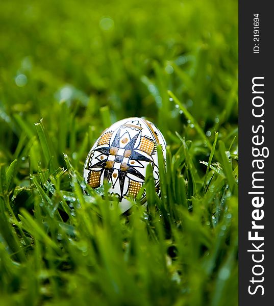 Traditional Easter Egg, painted with the symbol of the cross, on bright green grass covered with morning dew. Traditional Easter Egg, painted with the symbol of the cross, on bright green grass covered with morning dew