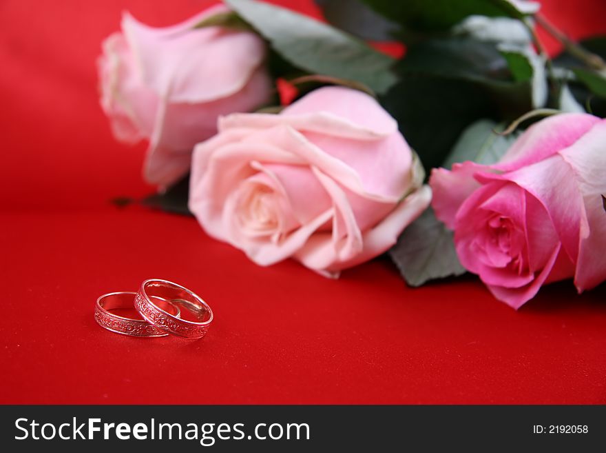 wedding rings and roses on red silk
