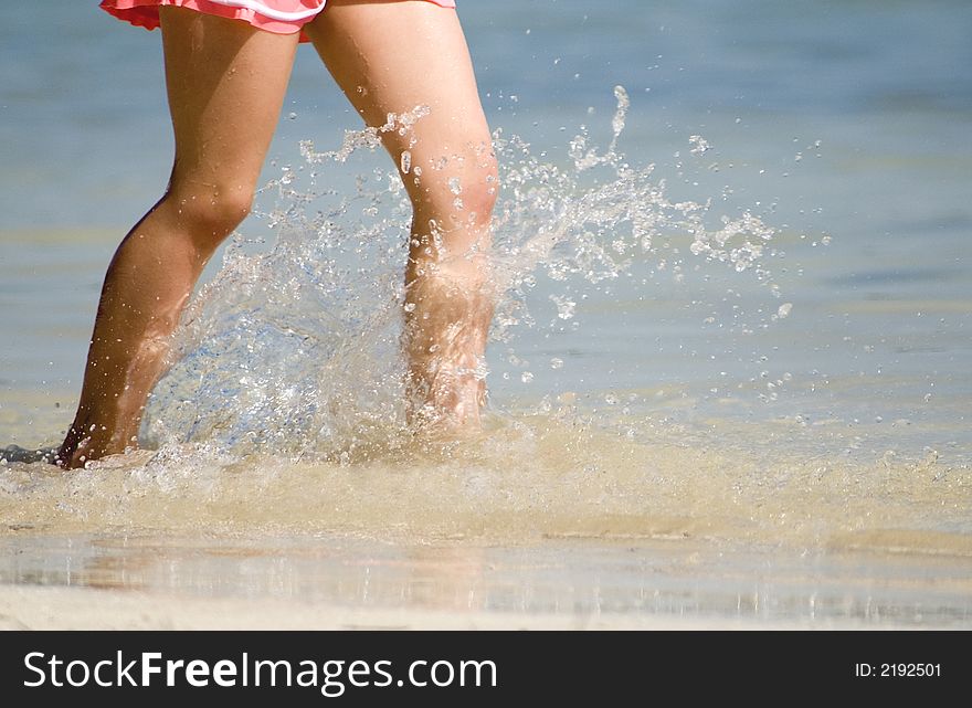 Girl wading and splashing along the beach. Girl wading and splashing along the beach