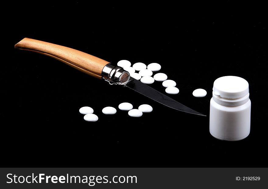 Knife and tablets on black background