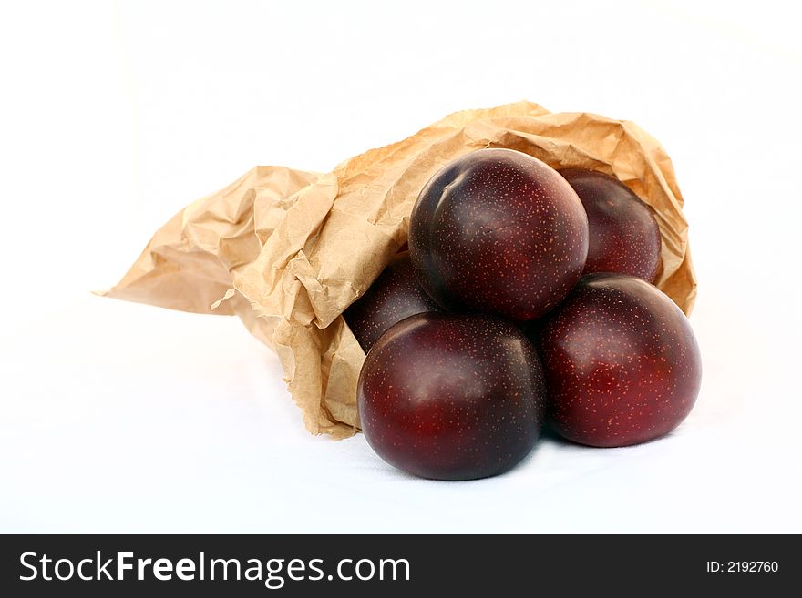 Plums in a paper-bag isolated on a white background. Plums in a paper-bag isolated on a white background.