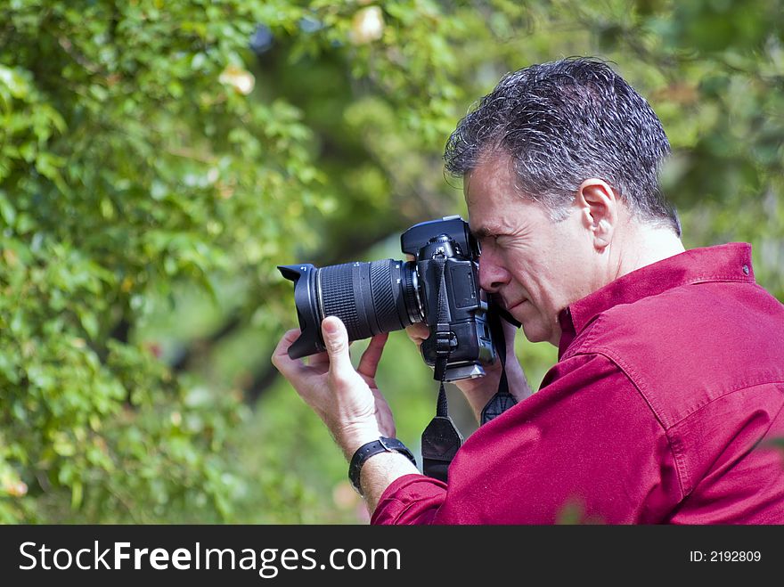 Professional photographer, with professional equiment, photographing a nature scene surrounded by lush green foliage. Professional photographer, with professional equiment, photographing a nature scene surrounded by lush green foliage.