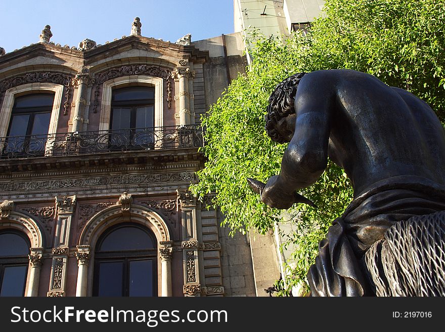 Sculpture of a man sitting in front of a colonial buiding in Mexico city, Mexico, Latin America. Sculpture of a man sitting in front of a colonial buiding in Mexico city, Mexico, Latin America