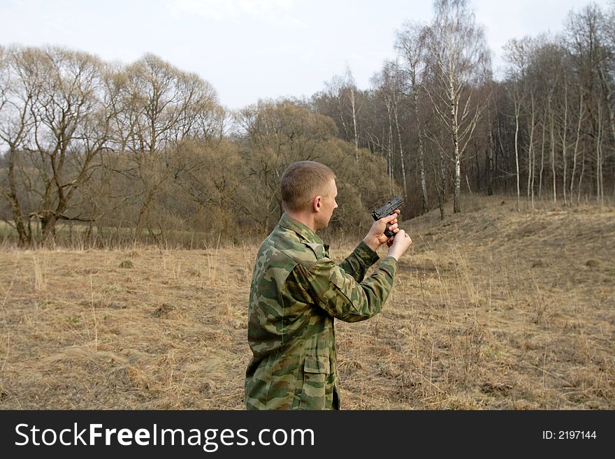 Man shoots from a pistol in a wood. Man shoots from a pistol in a wood