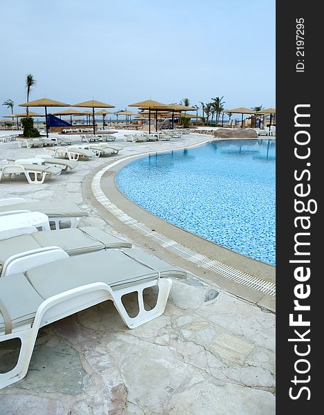 View at the resort pool with chairs and shades early in the morning. View at the resort pool with chairs and shades early in the morning