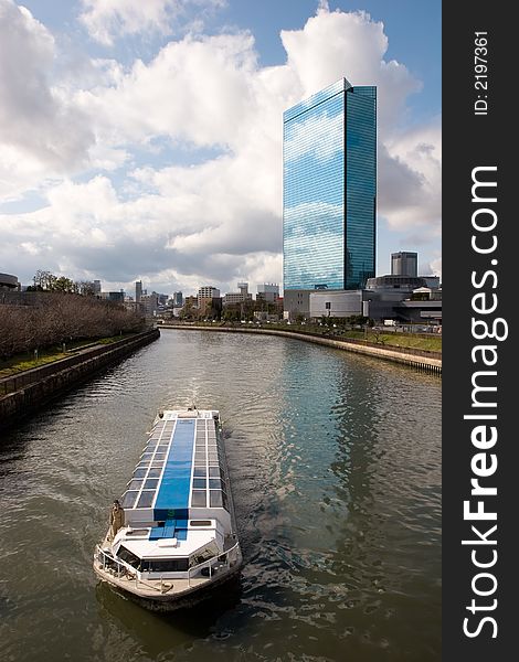 A scenic cruise boat on a river in Osaka Japan with modern building in background. A scenic cruise boat on a river in Osaka Japan with modern building in background.