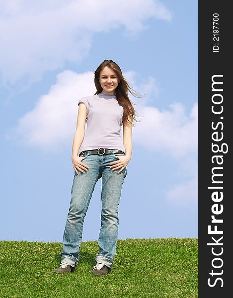 Portrait of the young pretty girl stand on a green grass on a background of the dark blue sky with clouds. Portrait of the young pretty girl stand on a green grass on a background of the dark blue sky with clouds