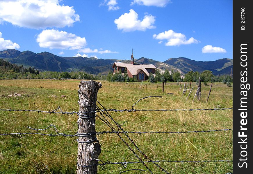 Wheat fields and blue cloud filled sky on Utah farmland with mountain backdrop