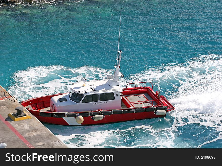 Red pilot boat cruising through aqua waters. Red pilot boat cruising through aqua waters