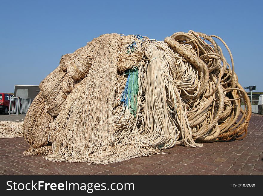 Pile of ropes and fishing nets on the quay of a fishing port