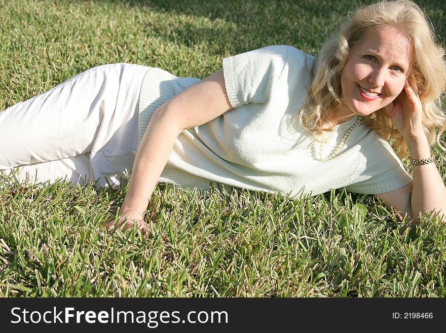 Shot of a blonde woman laying in grass