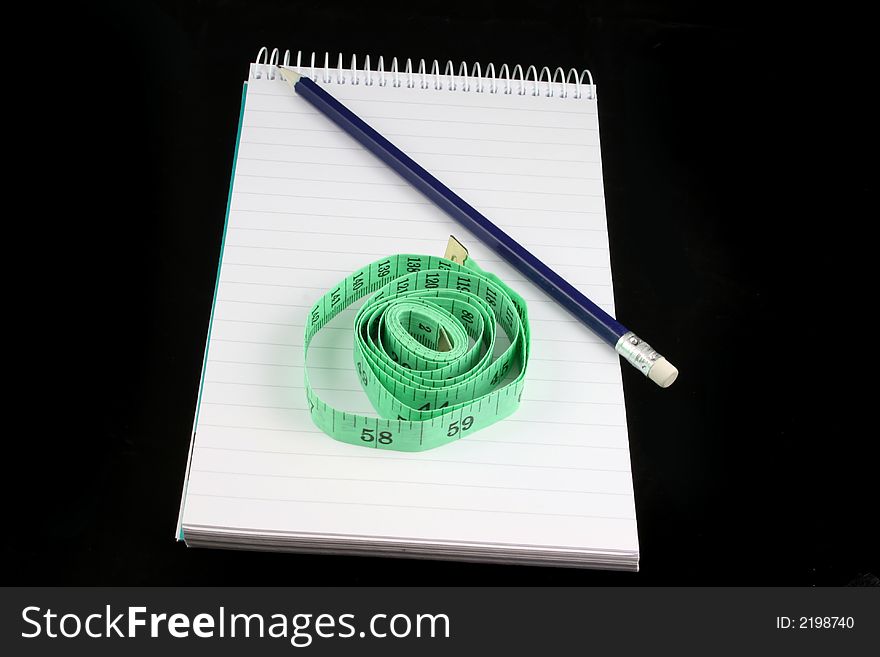 Notepad, pencil, and tape measure on a black background. Notepad, pencil, and tape measure on a black background