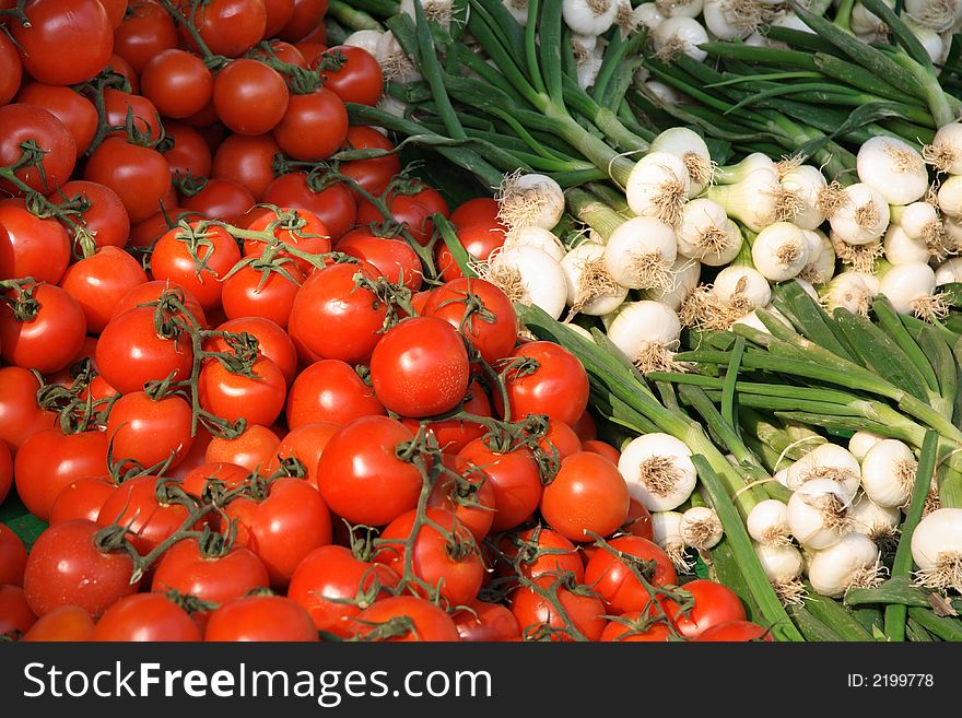 Tomatoes and bunches of spring onion on the market in sunny day. Tomatoes and bunches of spring onion on the market in sunny day