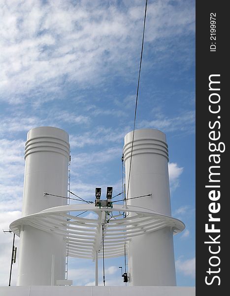 A pair of white ships smokestacks against clouds and sky