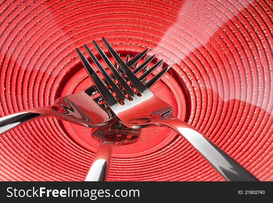 Three metal forks over red plate. Three metal forks over red plate