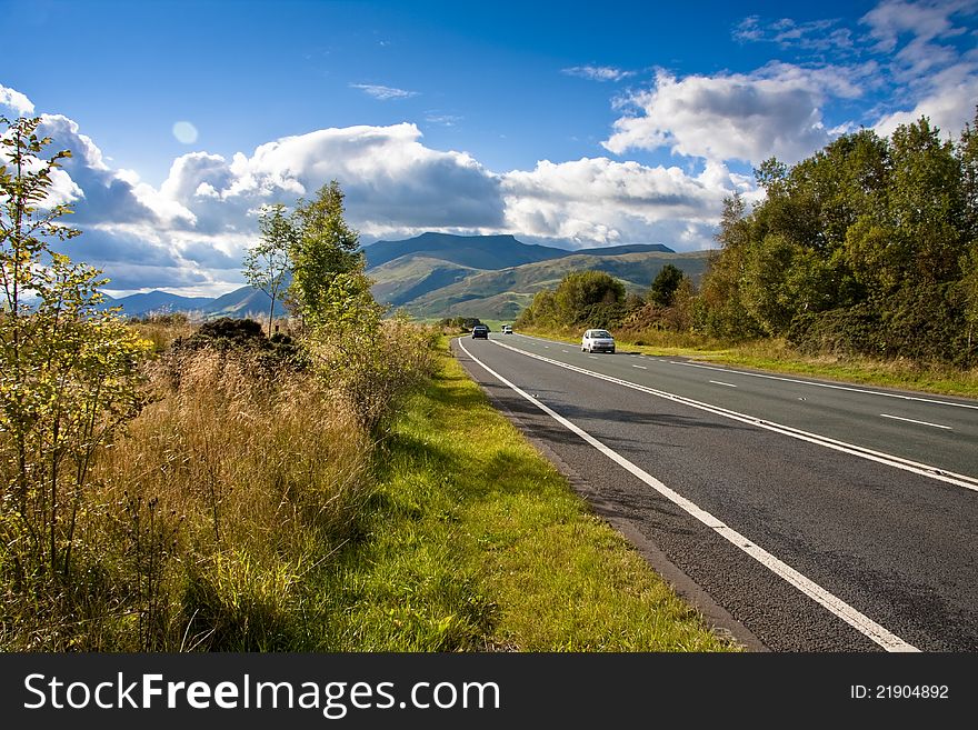 Scenic route into the cumbrian lake district blue sky and puffy clouds a popular holiday road. Scenic route into the cumbrian lake district blue sky and puffy clouds a popular holiday road
