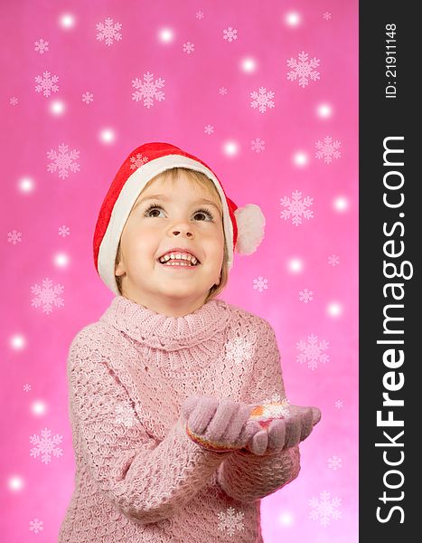 The little girl happy in Santa hat catches snowflakes. The little girl happy in Santa hat catches snowflakes.