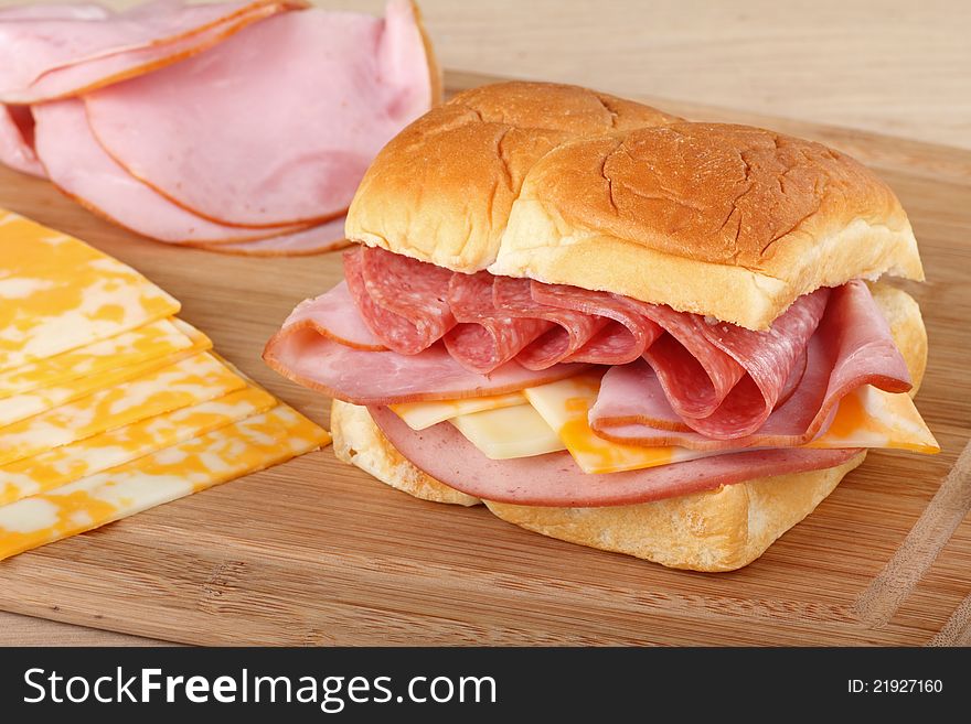Sandwich with ham, pepperoni, cheese and bologna with ham and cheese slices on the side. Sandwich with ham, pepperoni, cheese and bologna with ham and cheese slices on the side