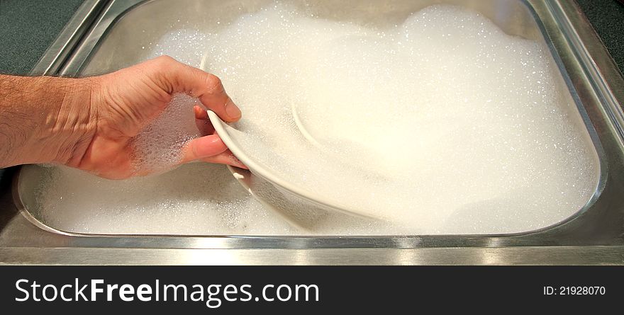 Closeup of a sink with a hand washing dishes. Closeup of a sink with a hand washing dishes