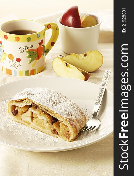 Fresh home-made apple strudel served with cup of tea and fresh apples