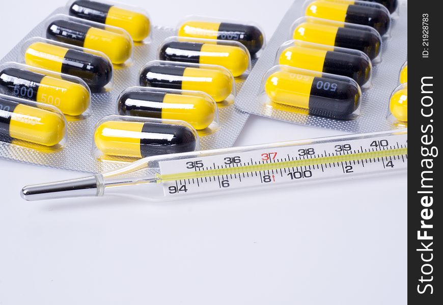 Close-up of thermometer and medicine in white background