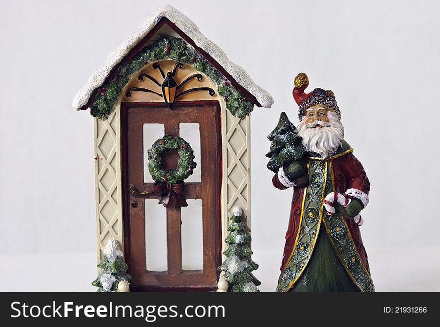 Old fashion santa holding tree and candy cane standing beside decorated door