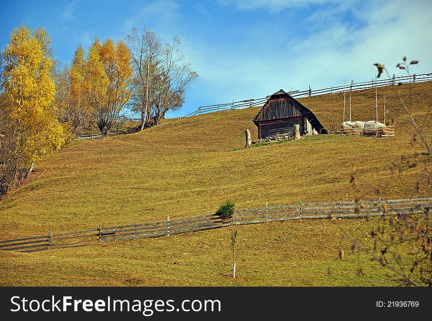 Autumnal green hill with wooden fence and cottage. Autumnal green hill with wooden fence and cottage