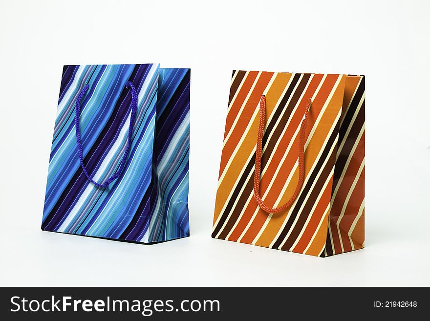 Two isolated striped paper gift bags of blue and orange. Two isolated striped paper gift bags of blue and orange.