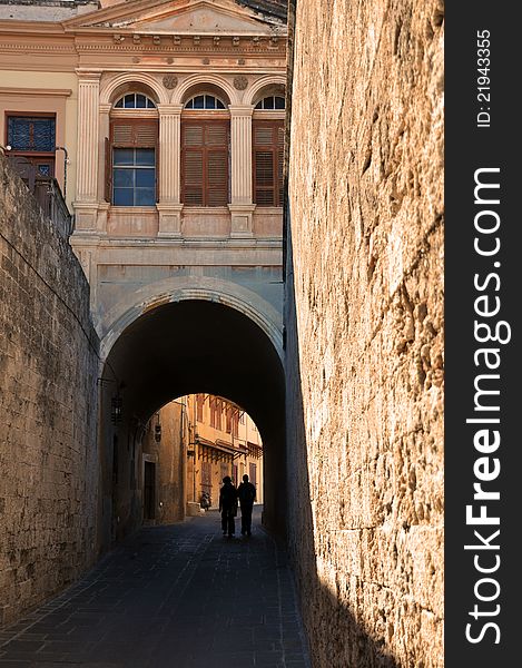 A silouette of a couple exploring the deserted alleyways which criss-cross the ancient walled city of rhodes in greece. A silouette of a couple exploring the deserted alleyways which criss-cross the ancient walled city of rhodes in greece