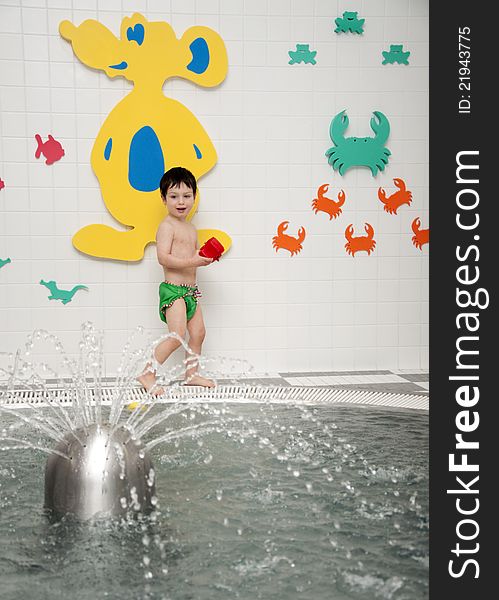 A small child, boy, playing with toys at an indoor swimming pool. A small child, boy, playing with toys at an indoor swimming pool.